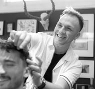 Adam laughing while working on a haircut