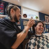 Kevin chatting with a woman while he styles her hair